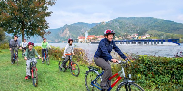 adventures-by-disney-europe-danube-river-cruise-itinerary-hero-01-biking-next-to-the-danube-river